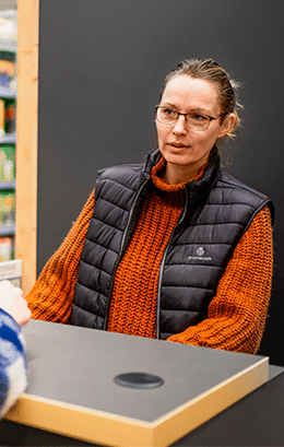 Collaboratrice PROMOCASH femme derrière un comptoir entrain d'écouter une cliente