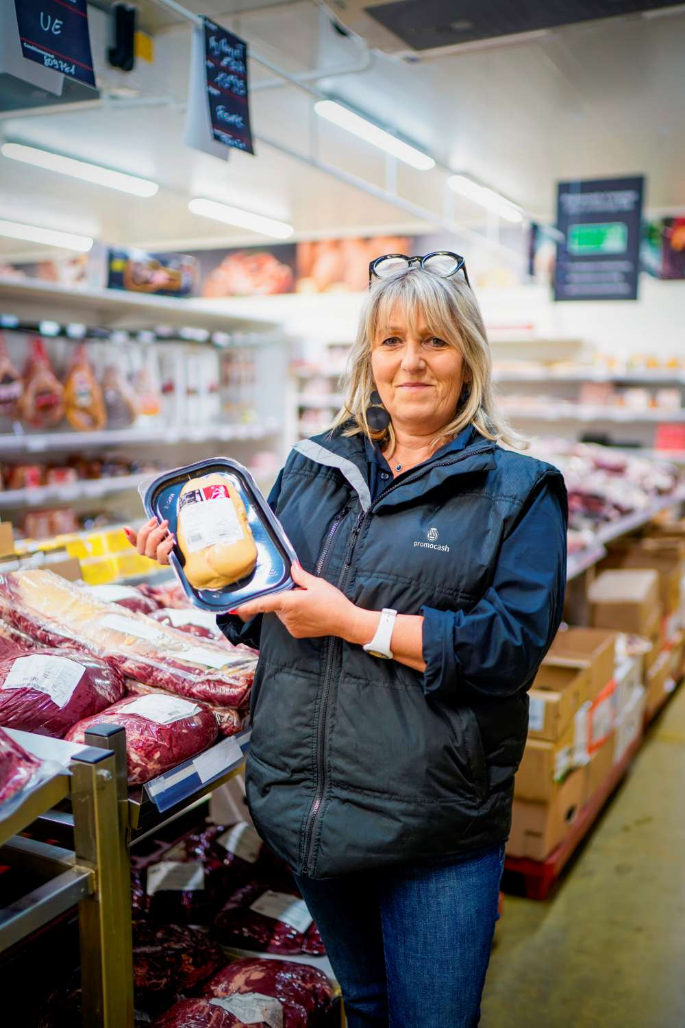 Collaboratrice Promocash tenant du poulet, dans le rayon charcuterie d'un magasin Promocash